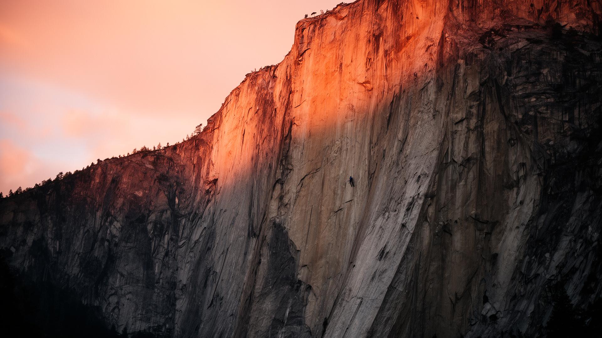 Dramatische Granit-Felswand im warmen Sonnenaufgangslicht mit winziger Kletter-Silhouette